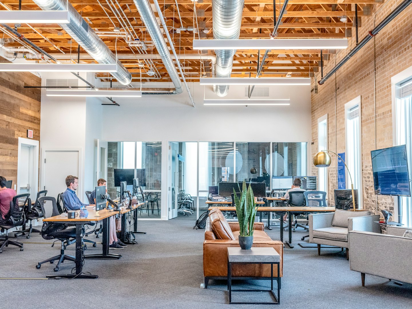 Hombres trabajando en computadoras en una oficina moderna de planta abierta.