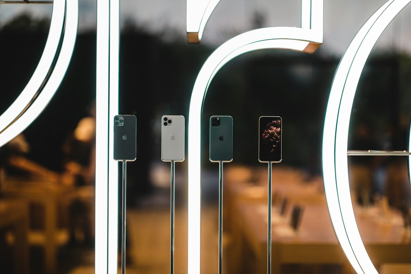 Teléfonos inteligentes en exhibición vertical sobre soportes metálicos en una tienda moderna.