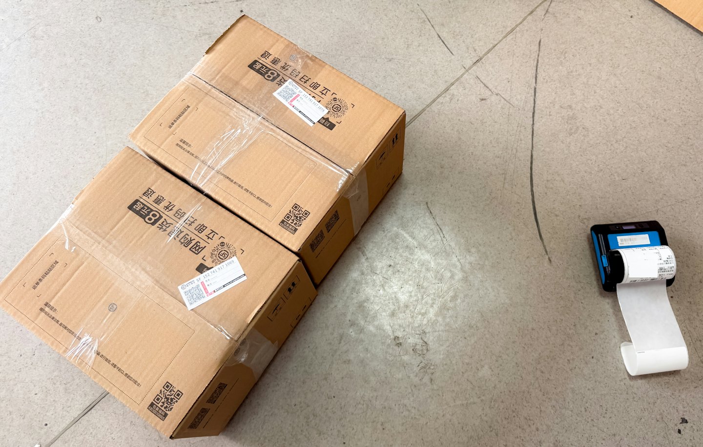 Cajas de envío y etiquetadora en piso de concreto.